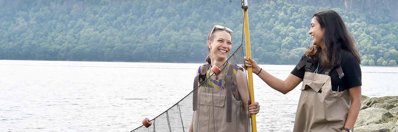two student smiling at each other holding a large seining net